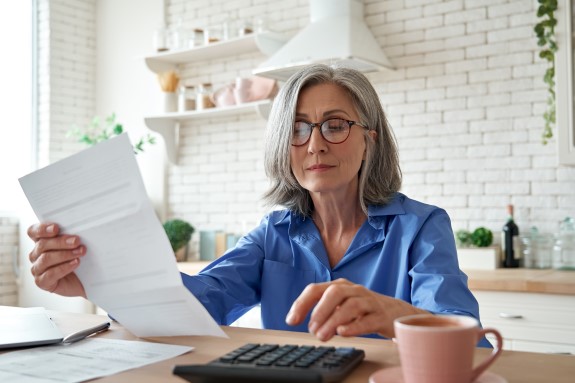 Woman at home reviewing document while using a calculator