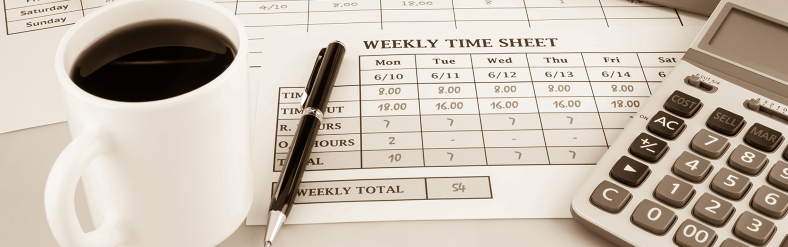 Coffee cup next to timesheet and calculator on desk