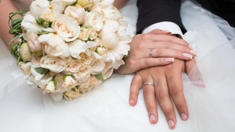 Wedding rings and bouquet symbolizing newlyweds planning shared finances and bank accounts after marriage.