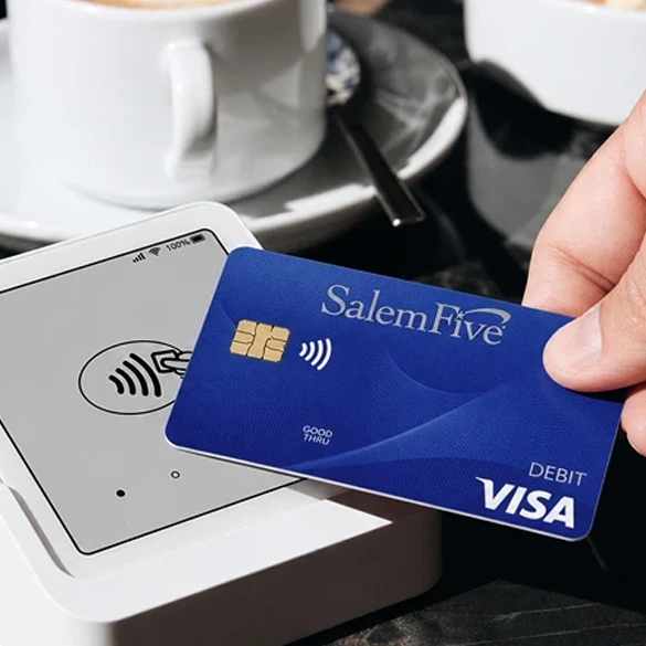 Salem Five Visa debit card being tapped on a contactless payment terminal at a café.