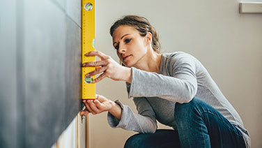 Woman using level on wall