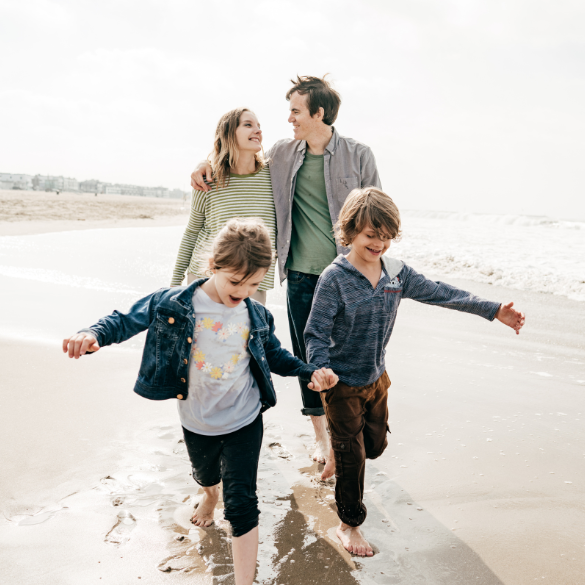 Family of four walking on the beach.