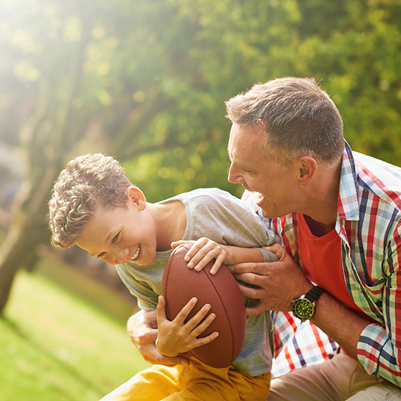 Happy dad and son playing with a football.