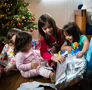 Four young girls opening Christmas presents.